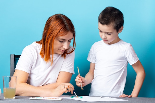 Mother and son paint with paint on blue background