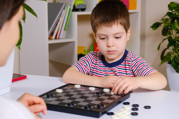 Mother and son play checkers in the house Board games for preschoolers and children