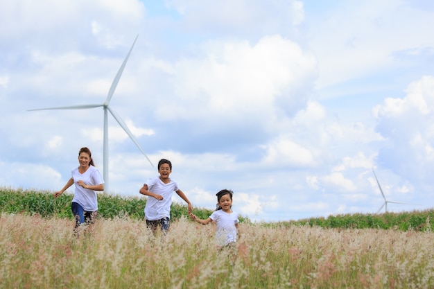 Mother and son playing in filed with huge wind turbine in background