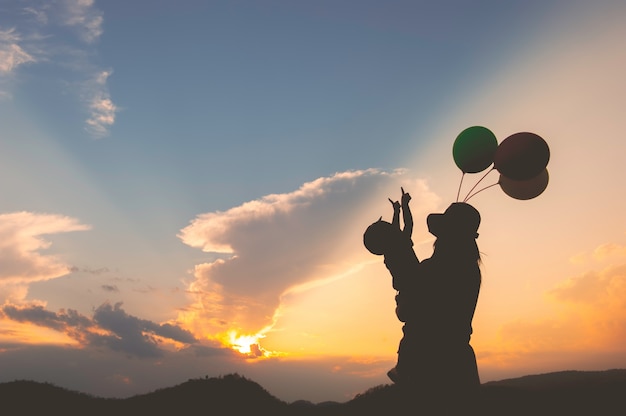 A mother and son playing outdoors at sunset silhouette