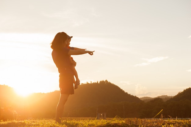 A mother and son playing outdoors at sunset