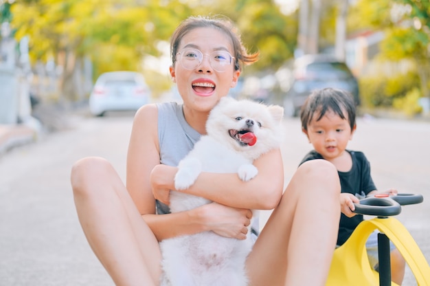 Madre e figlio che giocano sulla strada durante il giorno con il cucciolo di pomerania. concetto di famiglia amichevole.