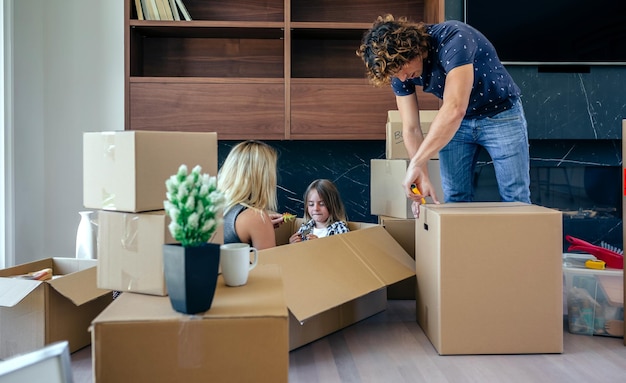 Mother and son playing sitting inside a moving box while the father unpacks