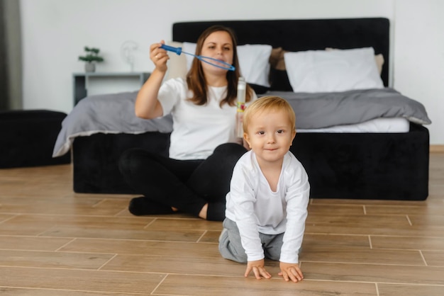 Mother and son playing with soap bubbles the child enjoys the soap bubbles family sitting at home pl