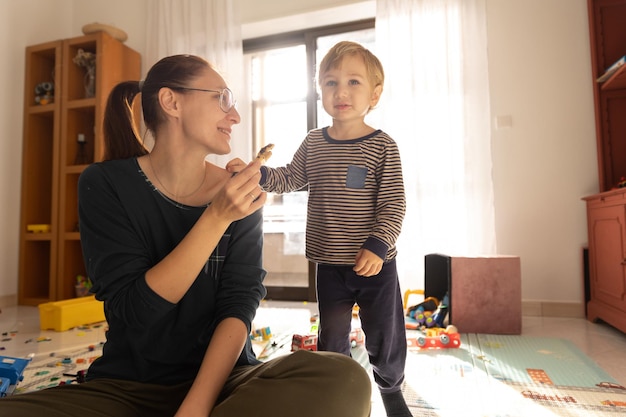 Mother and son in the playroom a woman holds a cookie and a boy looks ahead