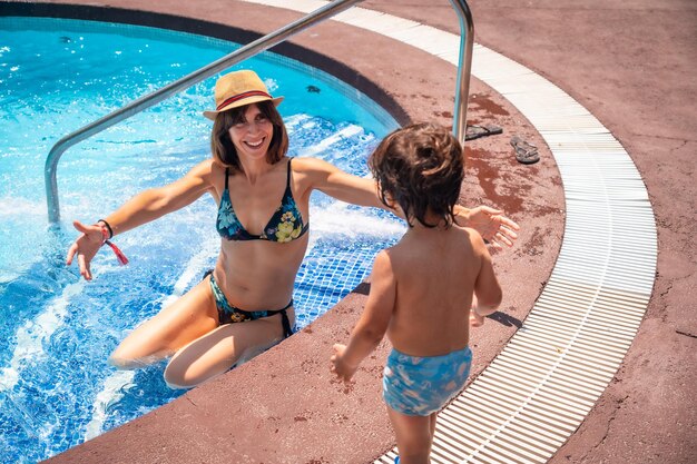 Mother and son in the pool on summer vacation moment of love giving his mother a kiss