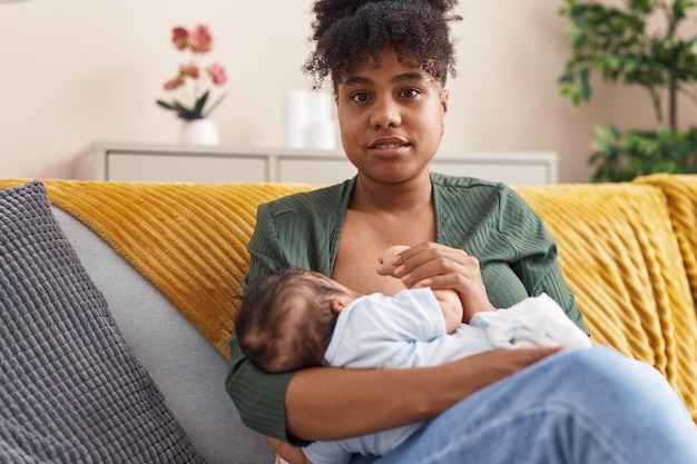 Photo mother and son sitting on sofa breastfeeding at home