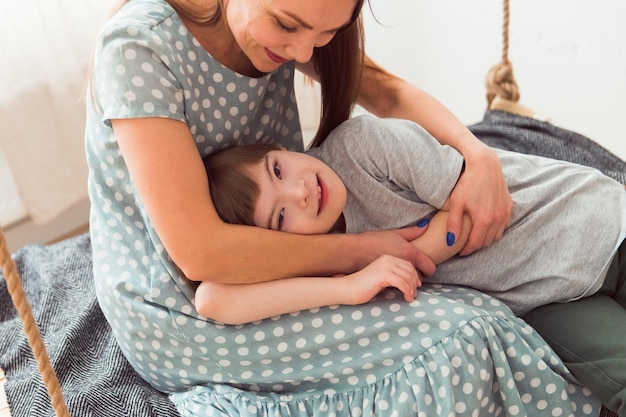 お母さんの膝の上に横たわっているダウンと一緒に男の子と一緒に時間を過ごす母と息子