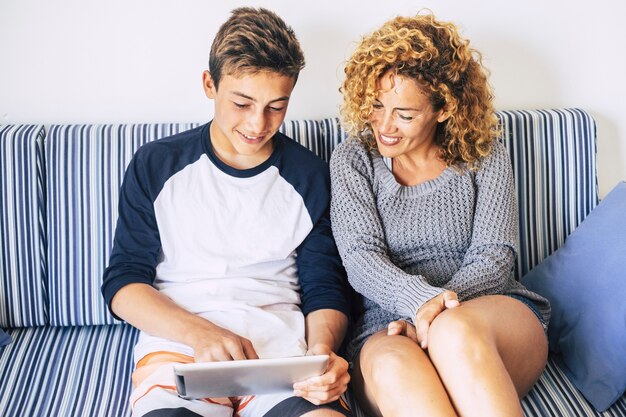 mother and son study together at home in the summer waiting the school restart again for another year. smile and happy using internet and a tablet technology. home real life