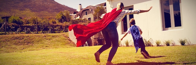 Mother and son in superhero costume playing in the backyard