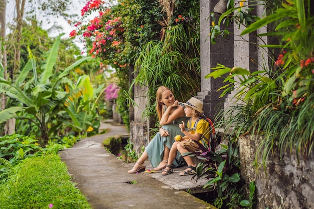 Mother and son tourists in bali walks along the narrow cozy streets of ubud bali is a popular tourist destination travel to bali concept traveling with children concept