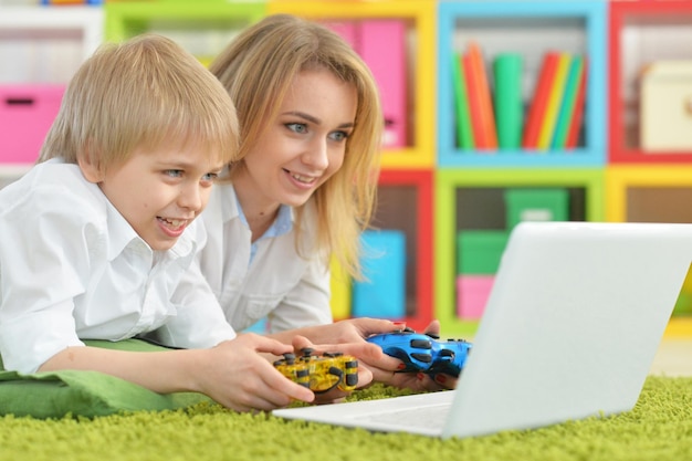 Мать и сын вместе используют ноутбук, играя в видеоигры