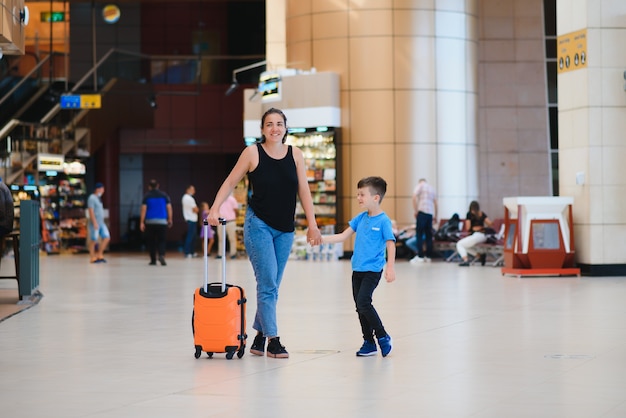 Mother and son waiting to board at departure gate of modern international terminal.