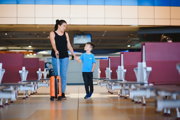 Mother and son waiting to board at departure gate of modern international terminal.