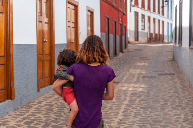 Mother and son walking past colored doors and windows to the streets in the village of Agulo in the north of La Gomera in summer Canary Islands