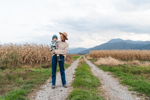 Mother and son walking playing together in agricultural field area Happy woman with child on road in nature Family traditions Concept sustainable lifestyle family bonding natural parenting