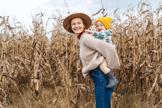 Mother and son walking playing together in corn field Family with kids fun Thanksgiving traditions and Halloween Concept organic gardening ecology sustainable lifestyle family bonding