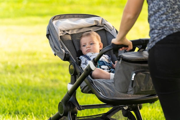 Mother and son walking with the baby stroller in the park