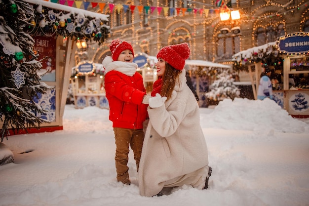 Mother and son in warm clothes have fun in winter at a snowy New Year's fair on Red Square in Moscow