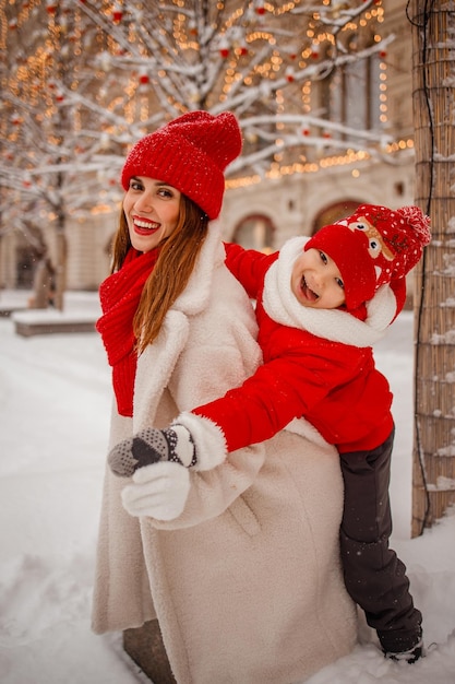 Mother and son in warm clothes have fun in winter at a snowy New Year's fair