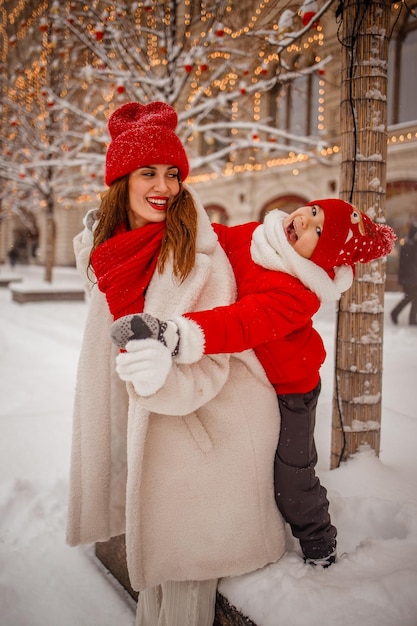 暖かい服を着た母と息子が雪の降る新年のフェアで冬を楽しむ