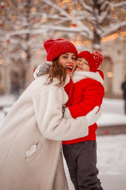 暖かい服を着た母と息子が雪の降る新年のフェアで冬を楽しむ