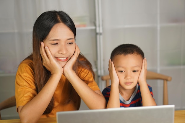 mother and son watching movies on computer at home table