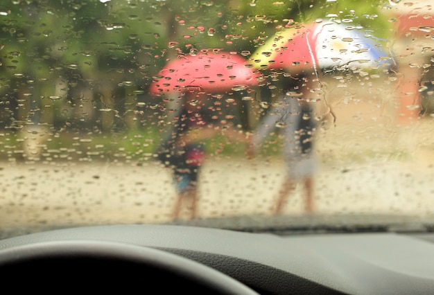 雨の中を歩いている傘を持つ母と息子