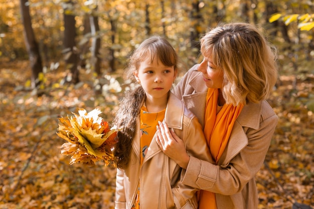 Mother soothes her unhappy sad daughter in autumn nature children depression concept