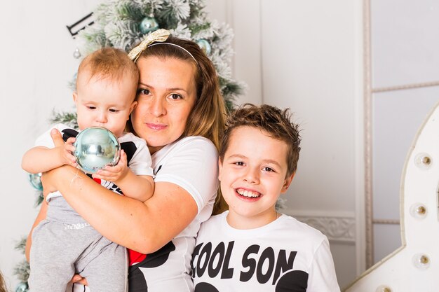 Photo mother spending time with sons near christmas tree.