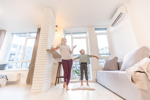 Mother in sportswear with daughter standing near the air conditioning