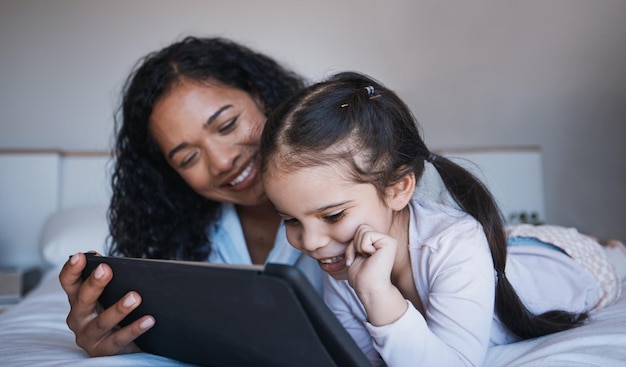 Mother tablet and kid relax on bed in home bedroom social media or online browsing Technology happiness and mom and girl with touchscreen for learning streaming film or video together in house