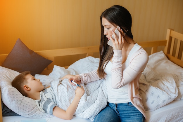 Photo a mother takes care of her child who has a fever and fever. disease and healthcare.