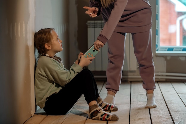 mother takes the phone from her preteen daughter in the attic at home