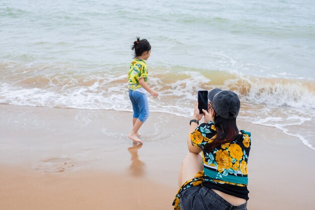 Mother takes pictures of her daughter on the beach.