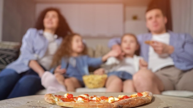 Mother takes pizza and enjoys watching movie with family