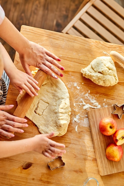 Mother teaches daughter prepare dough in the kitchen