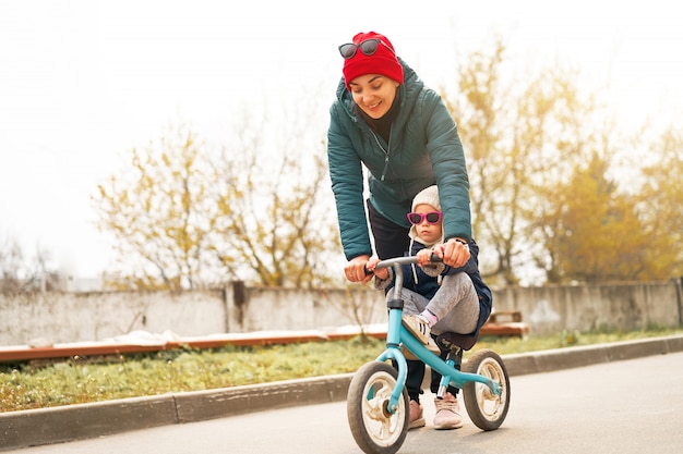 La madre insegna alla sua figlioletta ad andare in bicicletta