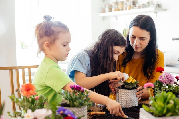 Mother teaches kids to take care of flowers and plants