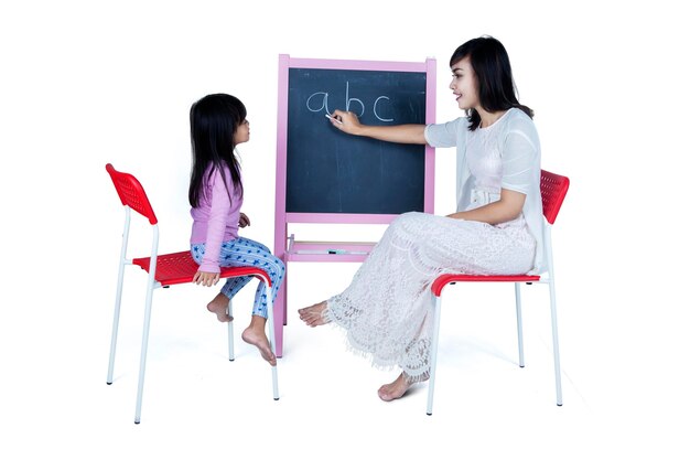 어머니 가  ⁇  배경 에 있는 블랙보드 위 에서 딸 을 가르치고 있다