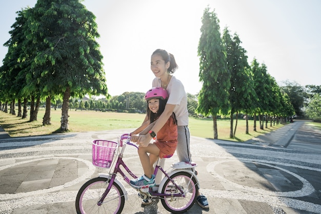 公園で自転車に乗ることを娘に教える母