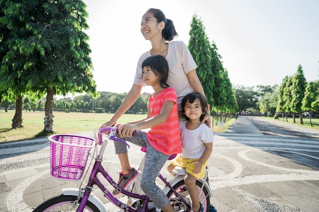 公園で自転車に乗ることを娘に教える母