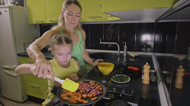 Mother teaching daughter smart girl learning to cook children to cook Neapolitan egg fried omelette