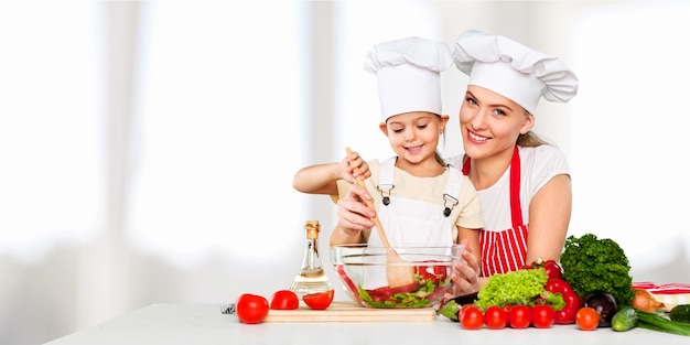 mother teaching kid daughter mixing salad at kitchen