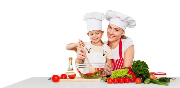 mother teaching kid daughter mixing salad at kitchen