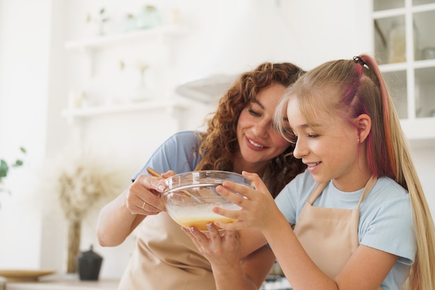 Mother and teen daughter making dough for pastry toghether in kitchen