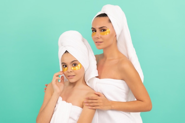 Mother and teen girl reduce eye bag. facial collagen skincare cosmetic. moisturizing skin. cosmetology. mom and daughter in terry towel use patch. beauty day in family spa. applying anti-fatigue mask.