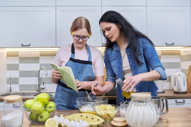 Mother and teenage daughter cooking at home in the kitchen