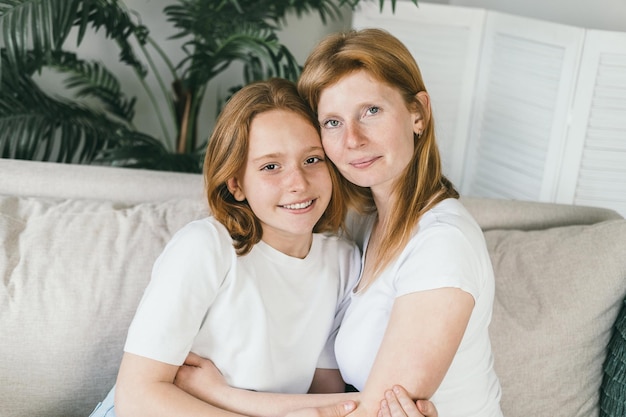 Mother and teenage daughter hugging at home on the couch