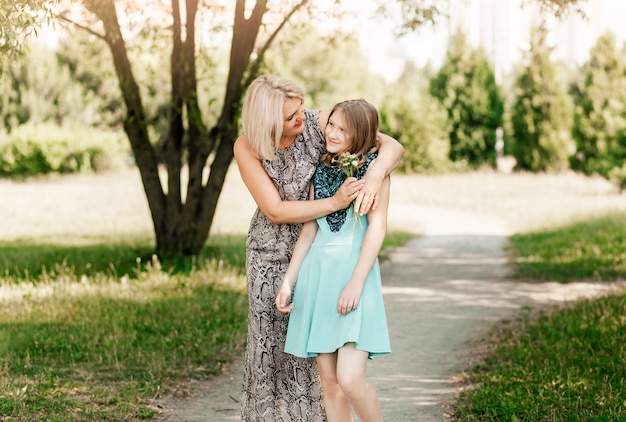 Mother and teenage girl walk together in the park in nature in the summer